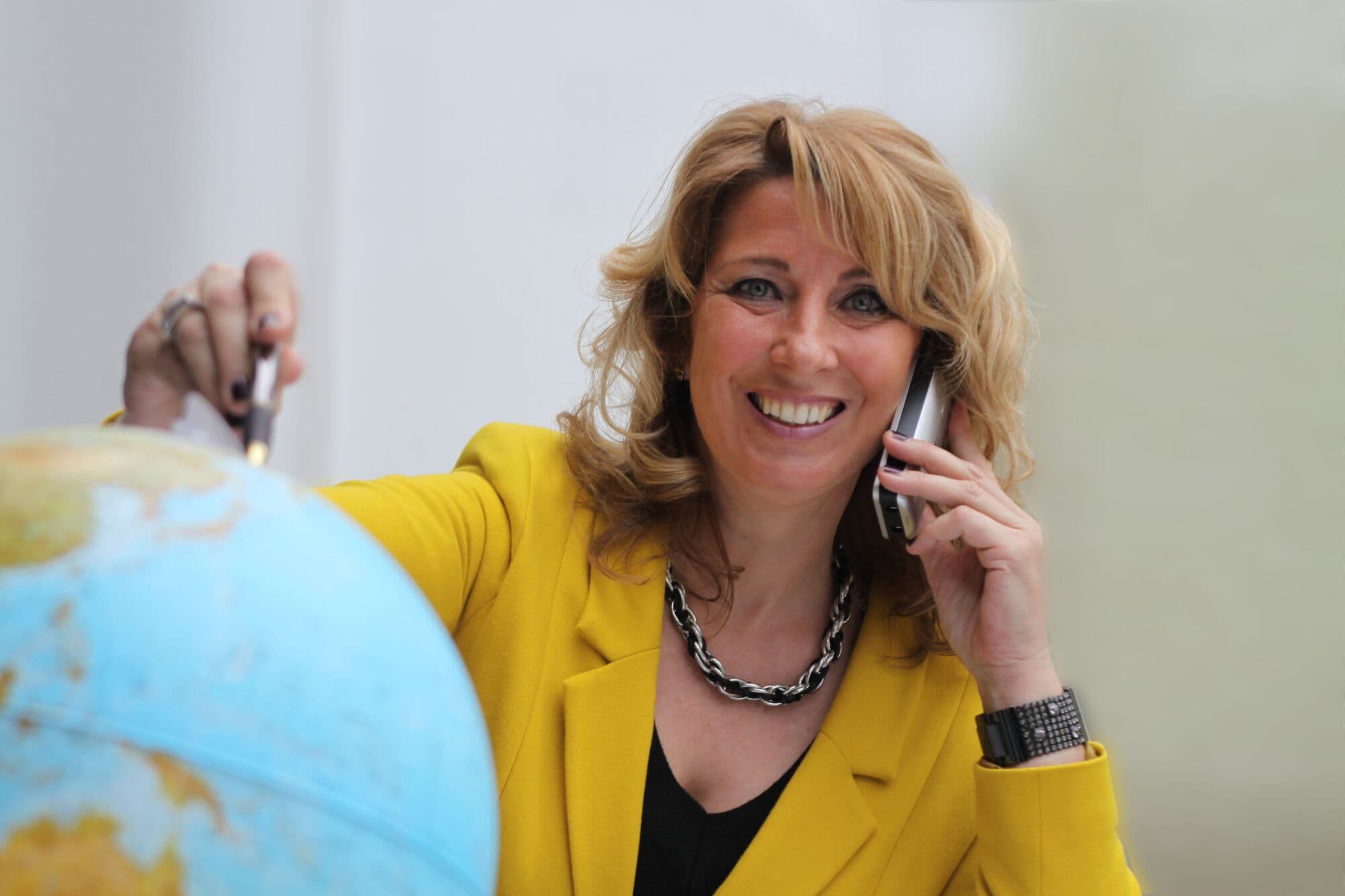 Andrea Mühlberger telefoniert, die andere Hand auf einem Globus